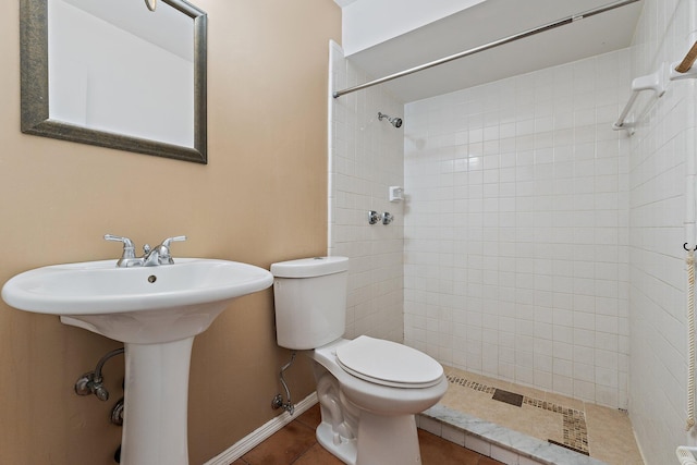 full bathroom with tile patterned floors, baseboards, toilet, and a tile shower