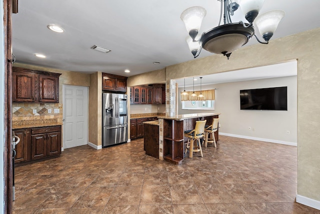 kitchen featuring baseboards, a kitchen breakfast bar, decorative backsplash, and stainless steel fridge with ice dispenser