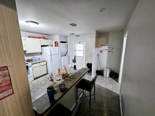 kitchen featuring white appliances, baseboards, light countertops, white cabinetry, and dark tile patterned floors