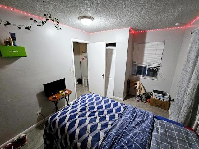 bedroom with tile patterned floors, baseboards, and a textured ceiling