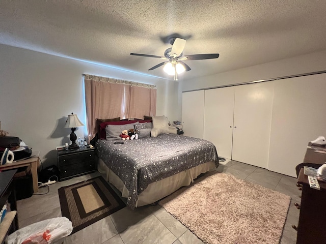 tiled bedroom with ceiling fan, a closet, and a textured ceiling