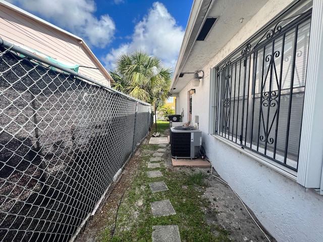 view of side of home with central AC unit and fence