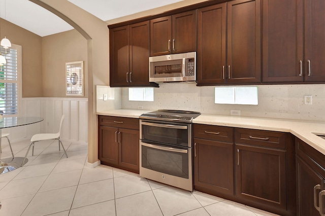 kitchen with stainless steel appliances, arched walkways, backsplash, and light countertops