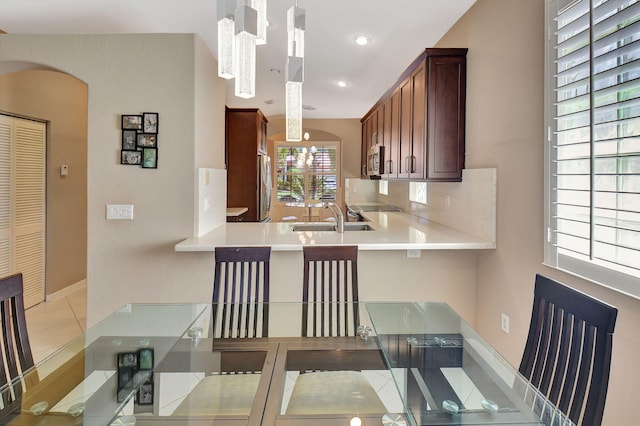 kitchen with light countertops, decorative backsplash, appliances with stainless steel finishes, arched walkways, and a sink