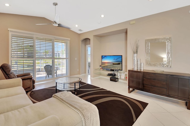 living area featuring arched walkways, light tile patterned flooring, a ceiling fan, and vaulted ceiling