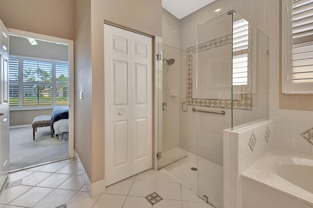 bathroom featuring tile patterned flooring, a garden tub, baseboards, and a stall shower