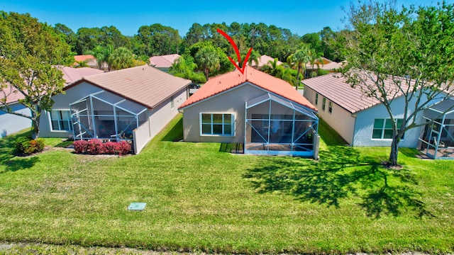 rear view of property featuring a tile roof, a yard, a lanai, and stucco siding