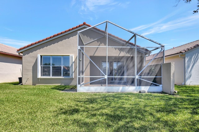 rear view of property with stucco siding, a yard, a lanai, and a tiled roof