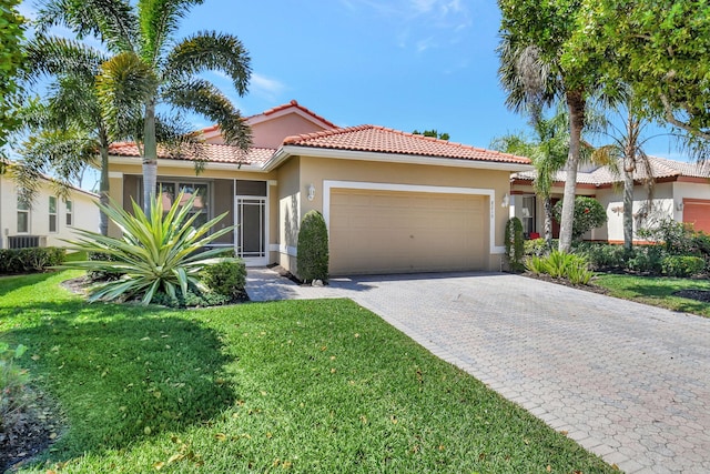 mediterranean / spanish home with stucco siding, decorative driveway, a garage, and a front lawn