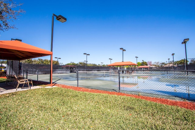 view of sport court with fence and a lawn