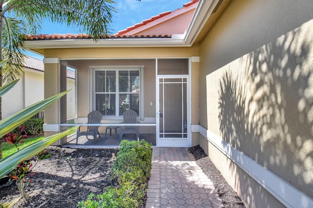 view of exterior entry featuring a tiled roof and stucco siding