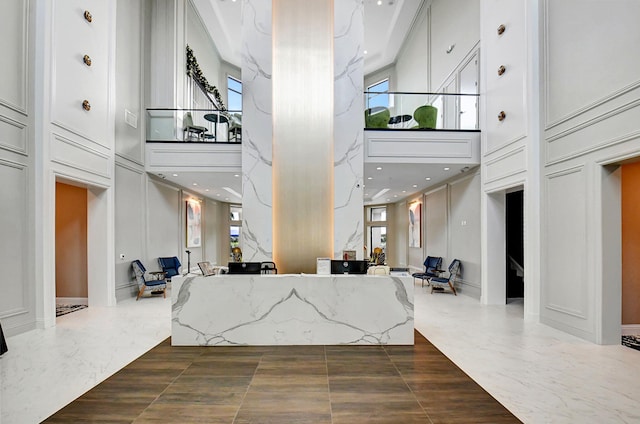 living room featuring a decorative wall, marble finish floor, and a high ceiling