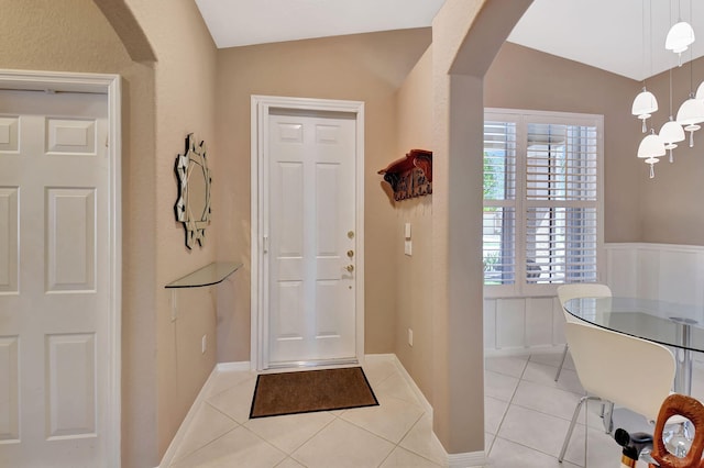 foyer entrance featuring vaulted ceiling, light tile patterned floors, and arched walkways