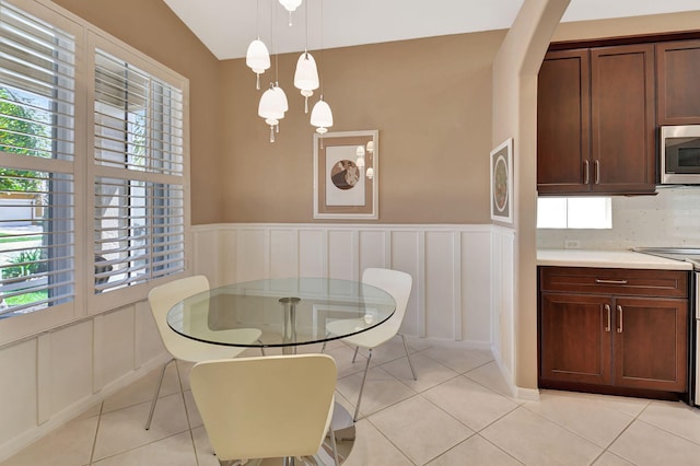 dining space with a wealth of natural light, a decorative wall, wainscoting, and light tile patterned floors