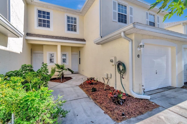 entrance to property featuring an attached garage and stucco siding