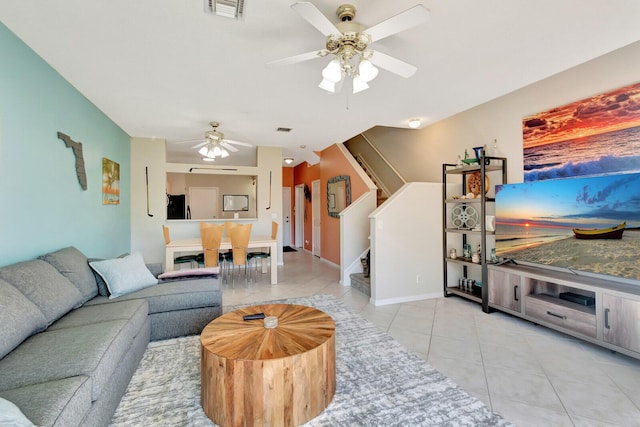 living area with visible vents, a ceiling fan, light tile patterned flooring, and stairs