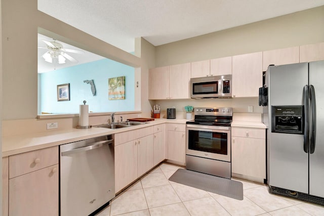 kitchen featuring light tile patterned floors, ceiling fan, a sink, light countertops, and appliances with stainless steel finishes