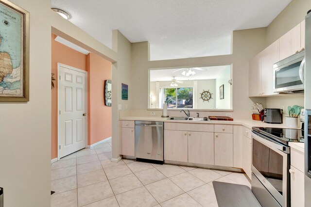 kitchen with light countertops, light tile patterned floors, appliances with stainless steel finishes, and a sink