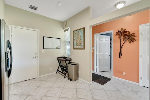 entryway with light tile patterned floors, visible vents, and baseboards