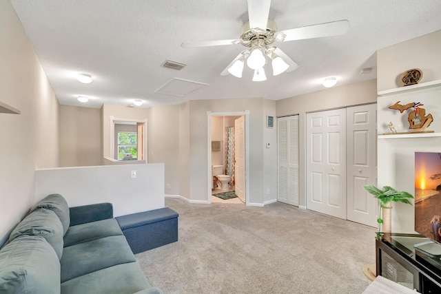 carpeted living area with visible vents, baseboards, a textured ceiling, and attic access