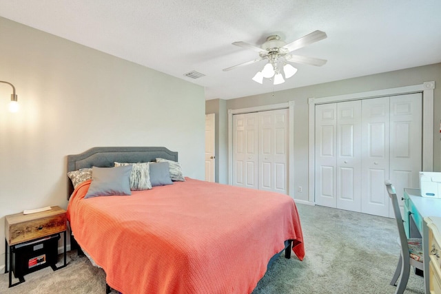 bedroom with visible vents, two closets, ceiling fan, and carpet floors