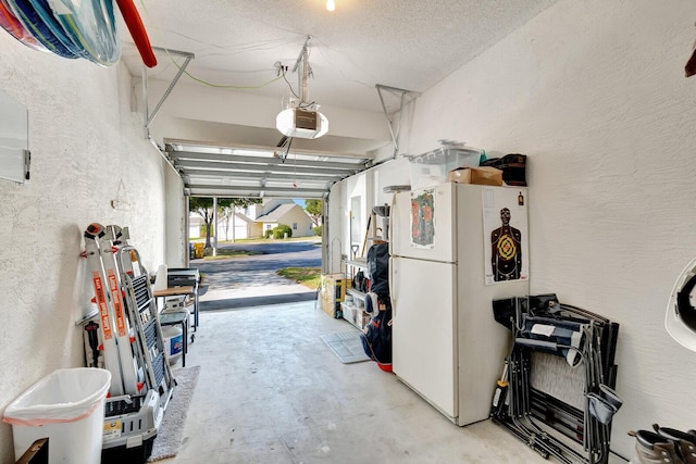 garage featuring a garage door opener, freestanding refrigerator, and a textured wall