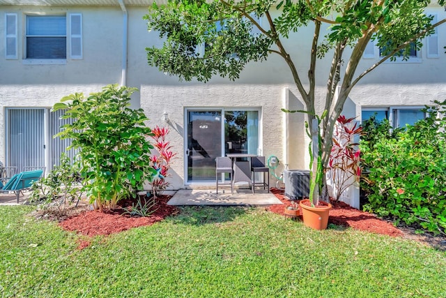 rear view of property featuring stucco siding, a patio, a lawn, and central AC unit