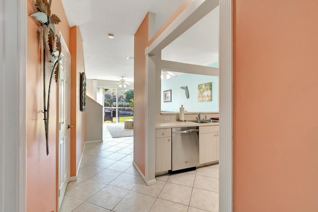 kitchen with stainless steel dishwasher, light countertops, light tile patterned floors, and a sink