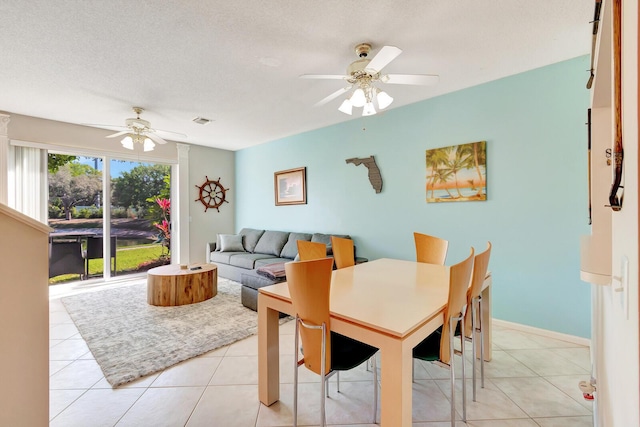 dining space with light tile patterned flooring, visible vents, a textured ceiling, and ceiling fan