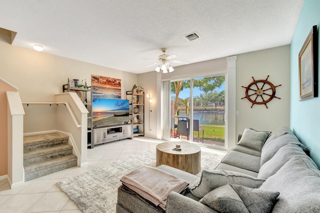 living room featuring visible vents, ceiling fan, stairway, light tile patterned floors, and a textured ceiling