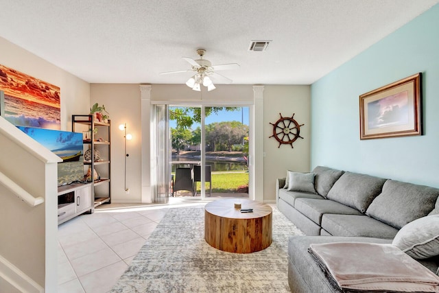 living area featuring light tile patterned floors, visible vents, a textured ceiling, and ceiling fan