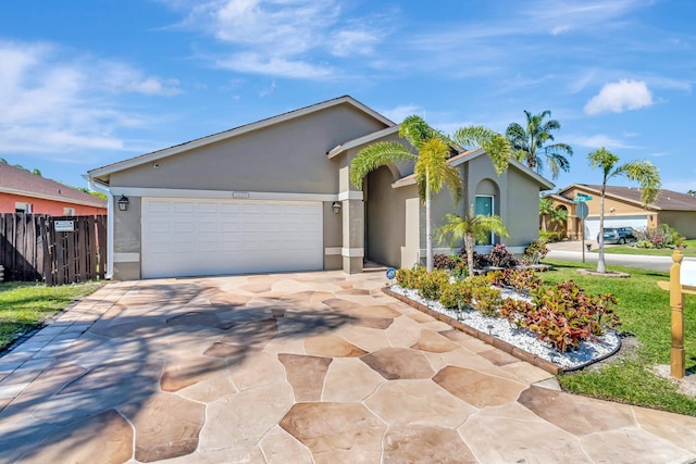 ranch-style home featuring stucco siding, a garage, driveway, and fence