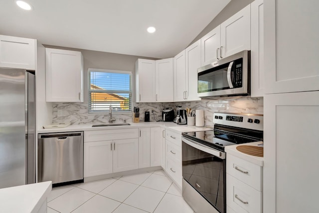 kitchen with a sink, stainless steel appliances, light countertops, white cabinets, and tasteful backsplash