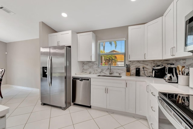 kitchen with a sink, decorative backsplash, light countertops, appliances with stainless steel finishes, and white cabinetry