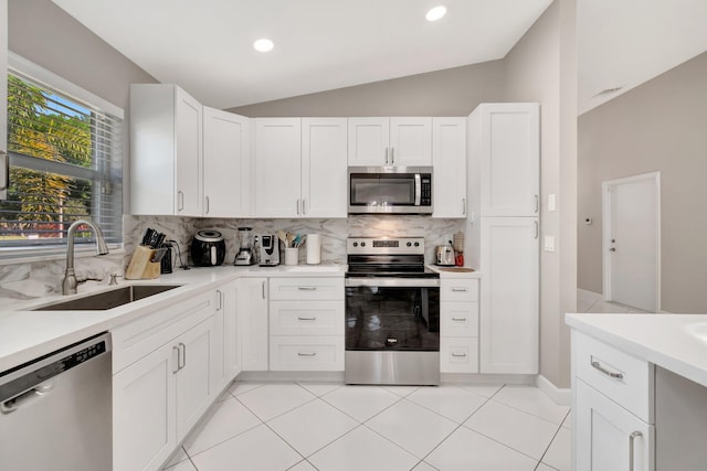 kitchen with light countertops, vaulted ceiling, decorative backsplash, stainless steel appliances, and a sink