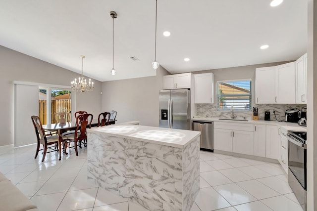 kitchen with light tile patterned flooring, a sink, stainless steel appliances, and vaulted ceiling