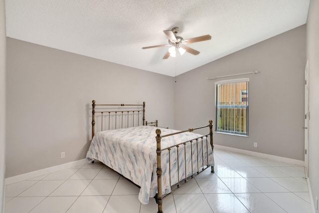 bedroom featuring lofted ceiling, light tile patterned floors, baseboards, and a textured ceiling