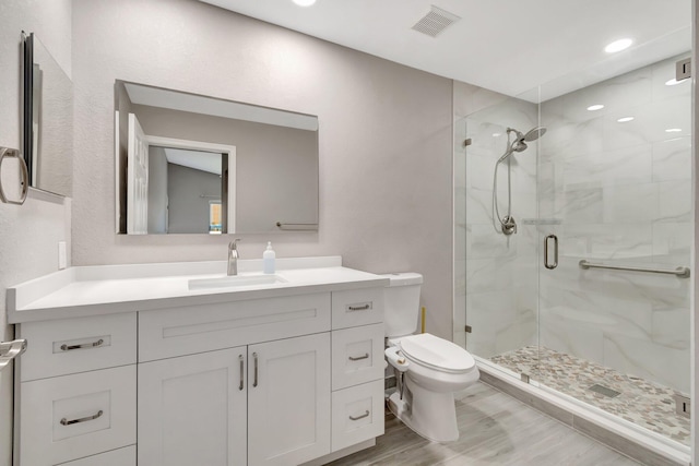 bathroom with vanity, wood finished floors, visible vents, a shower stall, and toilet