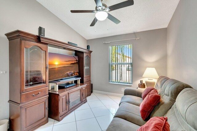 living area with light tile patterned floors, a ceiling fan, baseboards, vaulted ceiling, and a textured ceiling