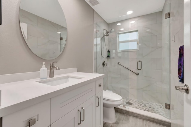 bathroom featuring vanity, a shower stall, toilet, and visible vents