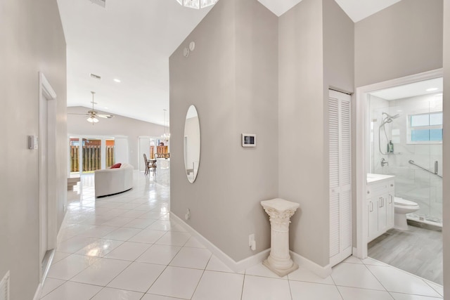 hall featuring vaulted ceiling, light tile patterned floors, visible vents, and baseboards