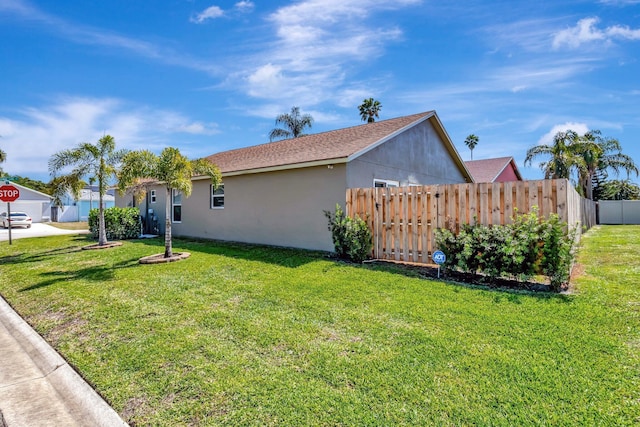 view of home's exterior with a yard, fence, and stucco siding