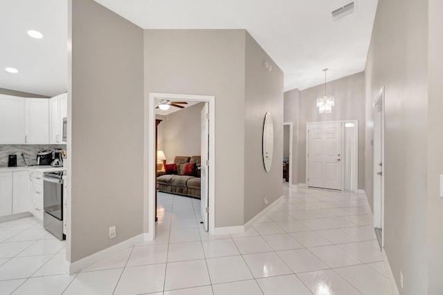 hall featuring light tile patterned floors, visible vents, an inviting chandelier, and baseboards