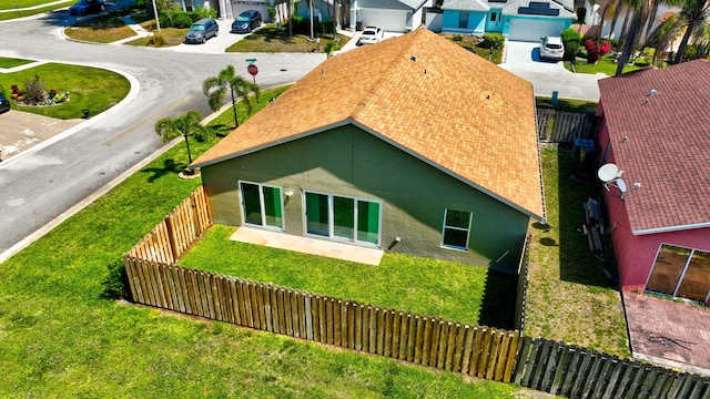 back of property with a residential view, fence private yard, stucco siding, a garage, and driveway