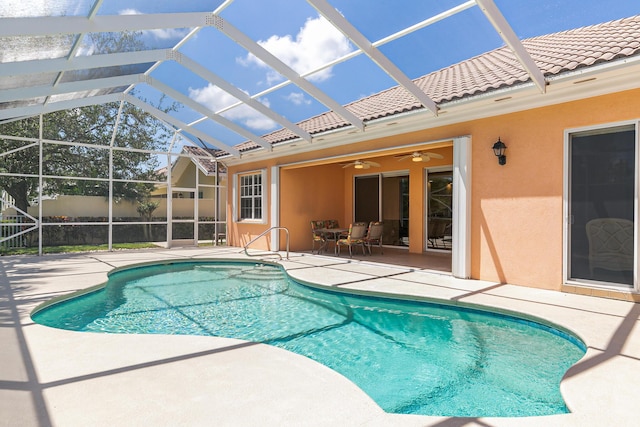pool with glass enclosure, a patio, and a ceiling fan