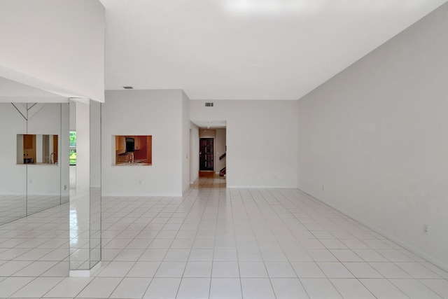 unfurnished living room featuring light tile patterned floors, visible vents, and stairway