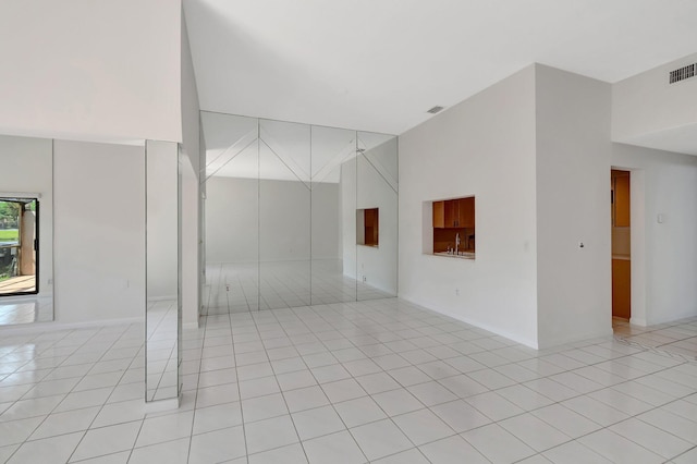 unfurnished room featuring light tile patterned floors, visible vents, and a towering ceiling