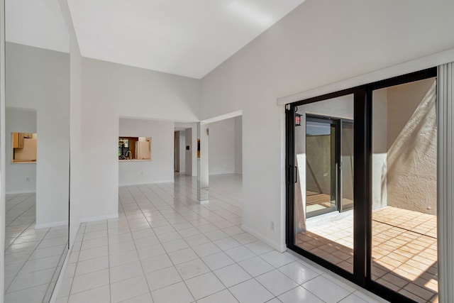 spare room with light tile patterned floors, a wealth of natural light, and a towering ceiling