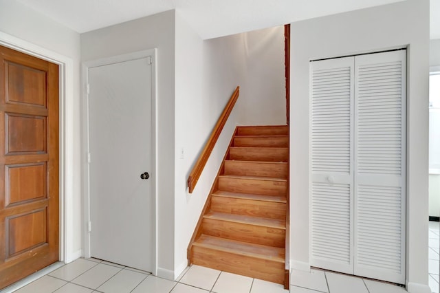 stairway with tile patterned floors and baseboards