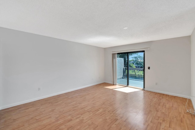 unfurnished room with baseboards, a textured ceiling, and light wood finished floors